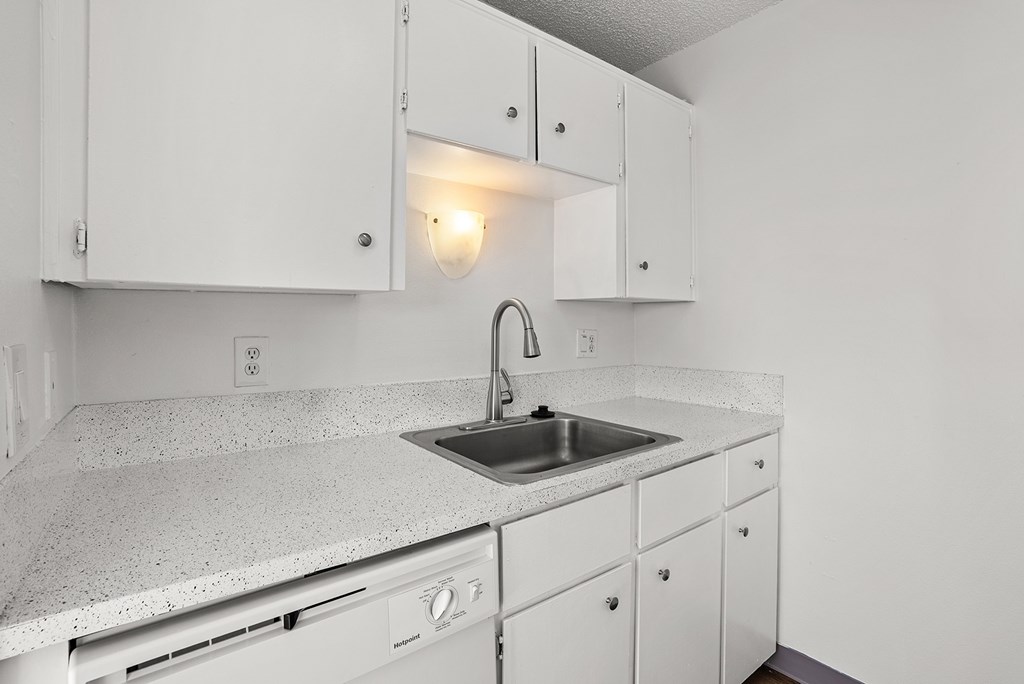 A kitchen with white cabinets and a granite countertop.