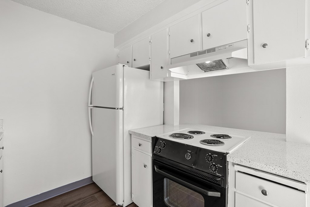 A white kitchen with a refrigerator, oven, and stove.