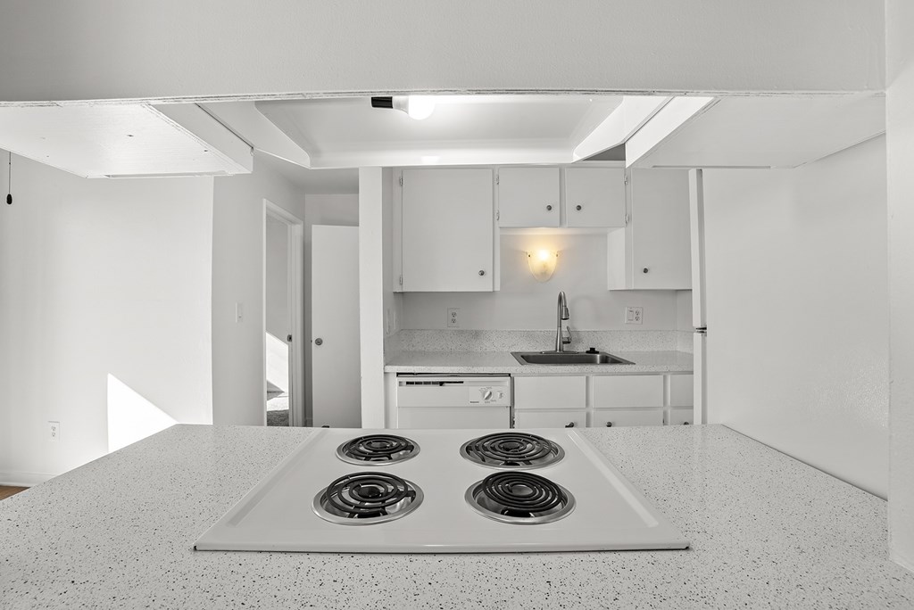 A kitchen with white cabinets and a white stove top.