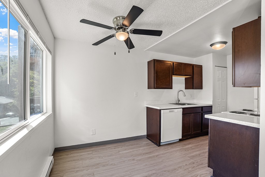 Kitchen with a ceiling fan and wooden floors.