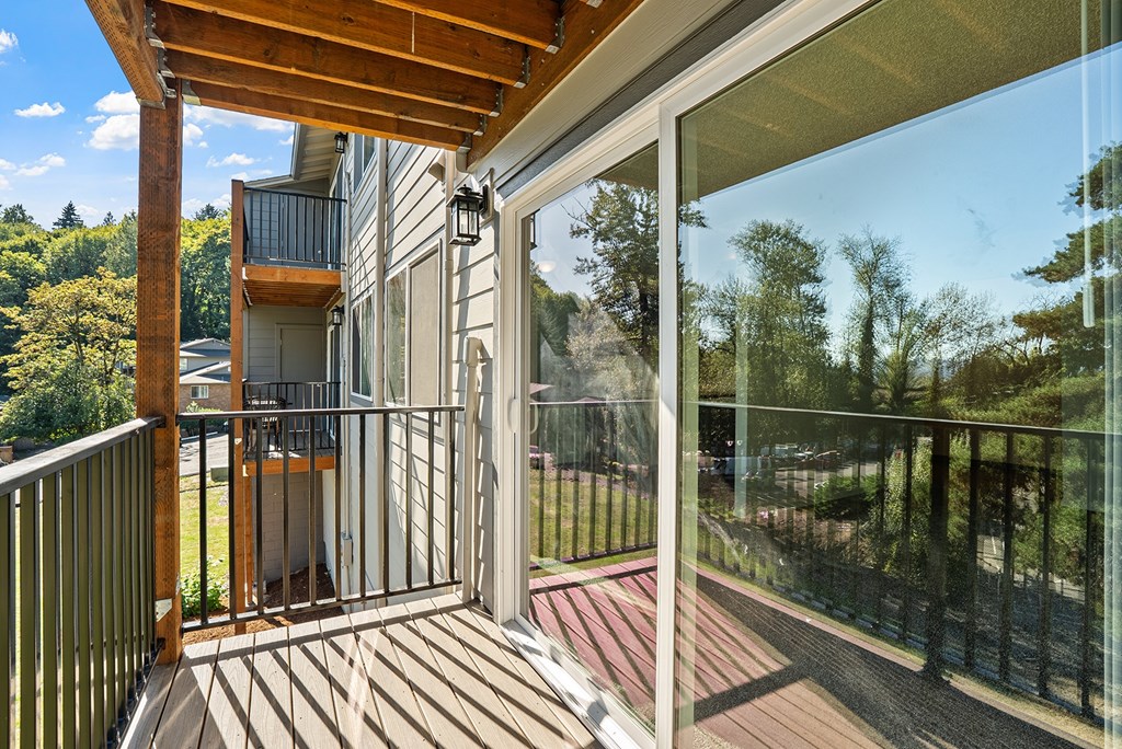 A balcony with a glass door and a wooden railing.