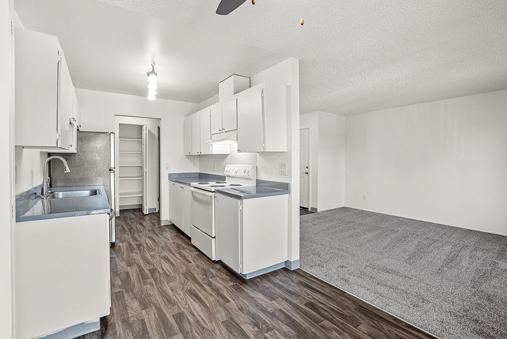 A kitchen with white appliances and wooden floors.