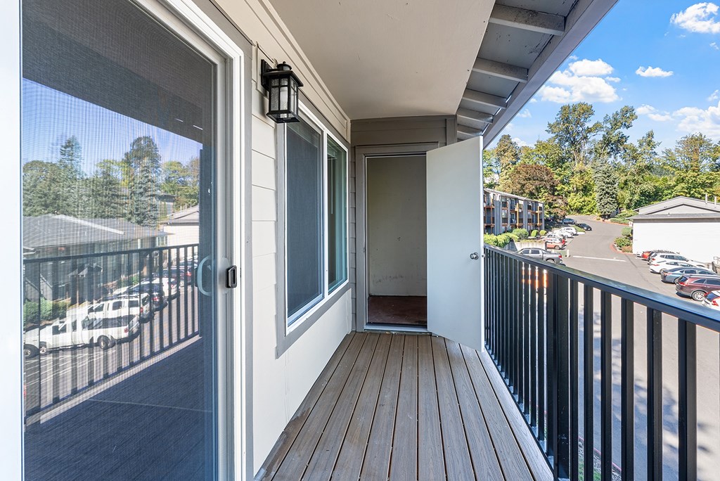 A balcony with a sliding glass door leading to a deck.