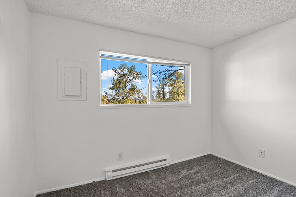 A bedroom with a window showing a tree outside.