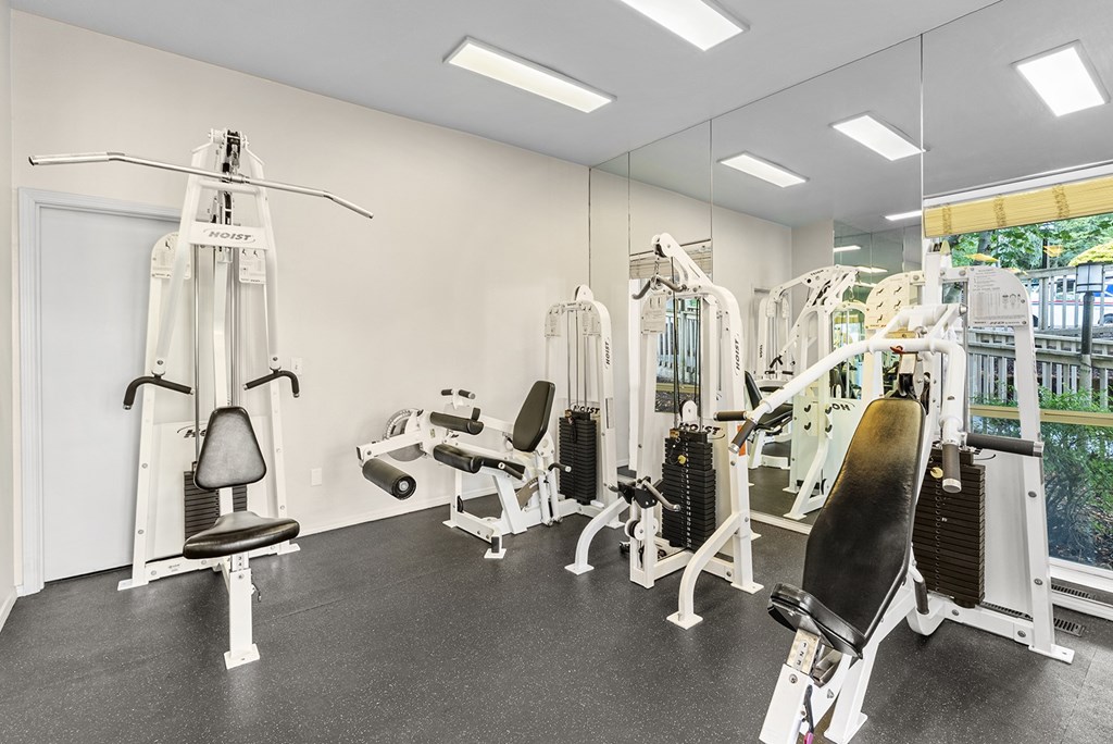 A gym with a variety of equipment including a leg press machine and a chest press machine.