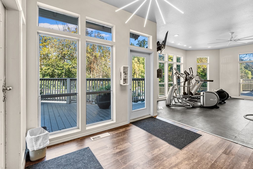 A spacious room with a gym setup and a view of a deck through the sliding glass doors.