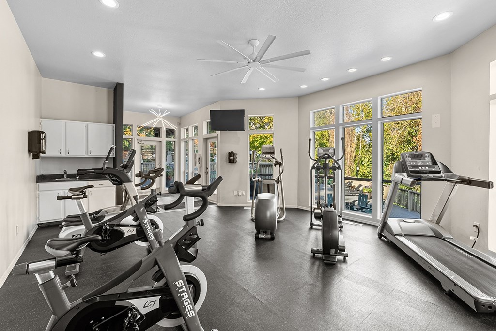 A gym with a row of stationary bikes and a treadmill.