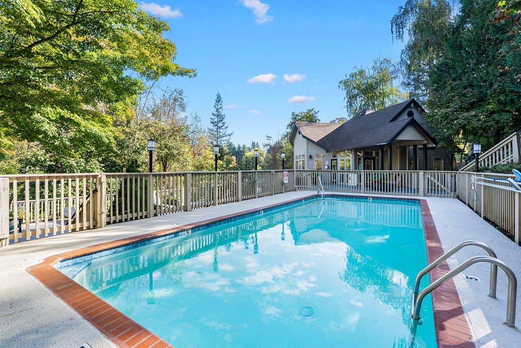 A small pool surrounded by a fence and trees.