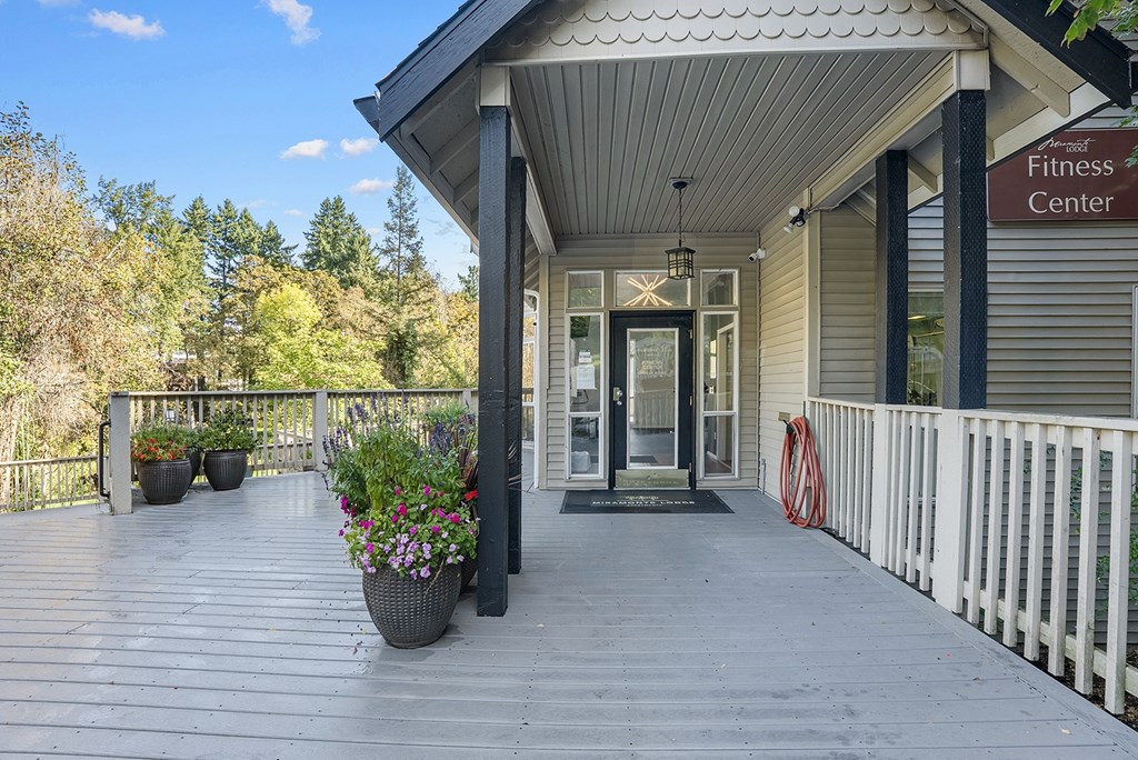 A fitness center entrance with a wooden deck and potted plants.