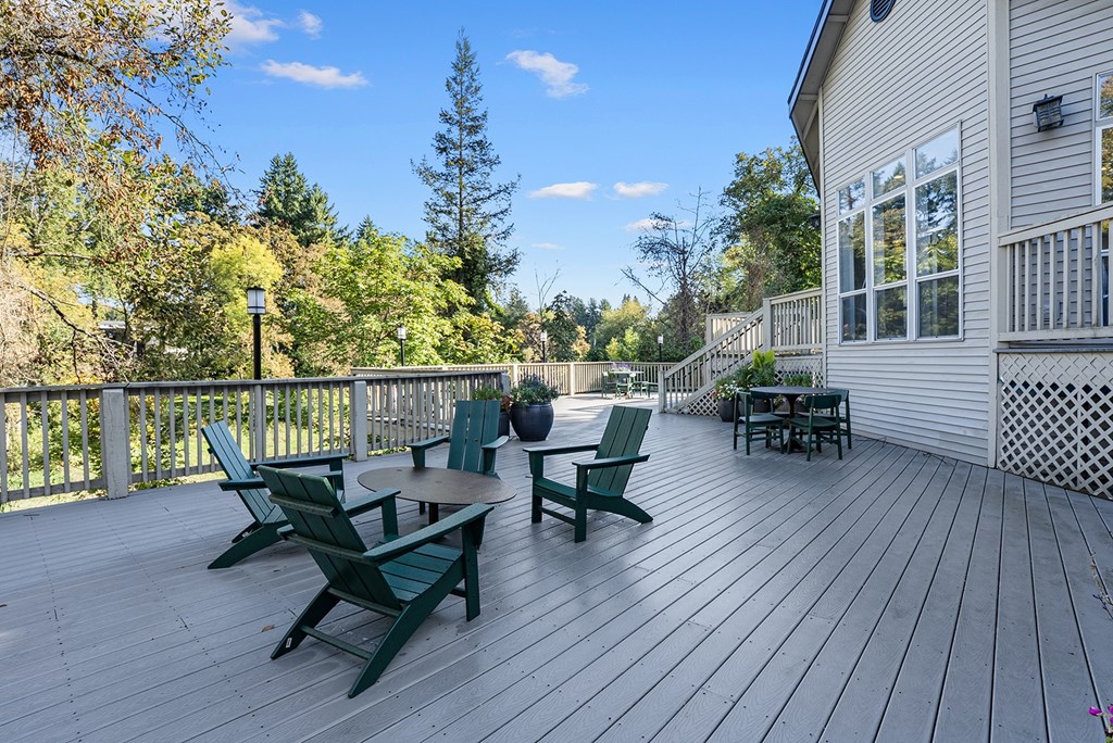A wooden deck with green chairs and a table.