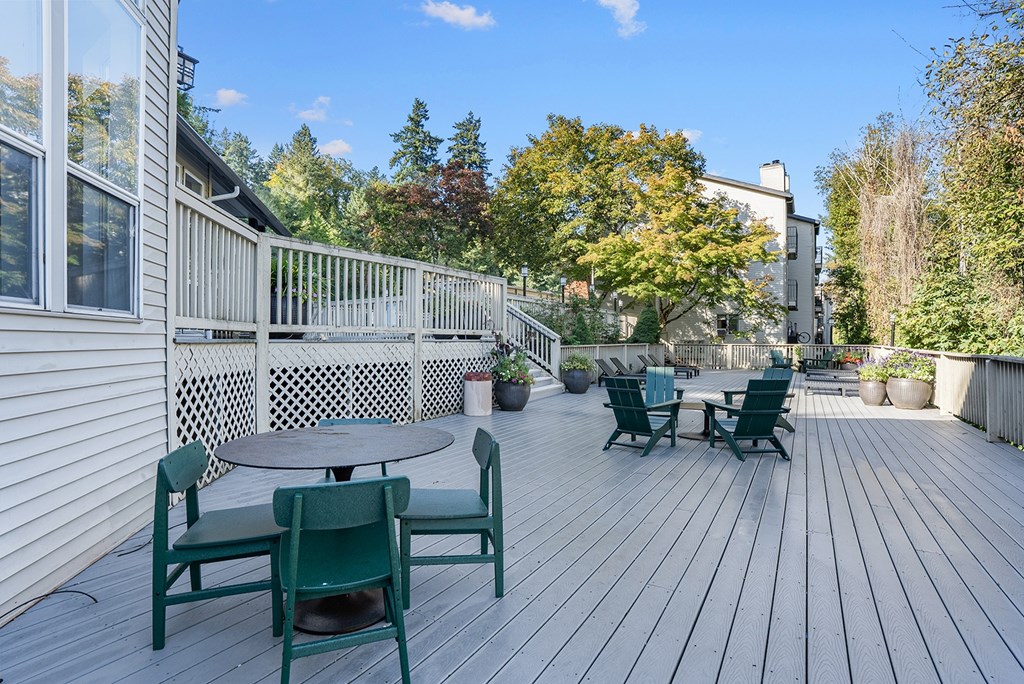 A wooden deck with green chairs and a table.