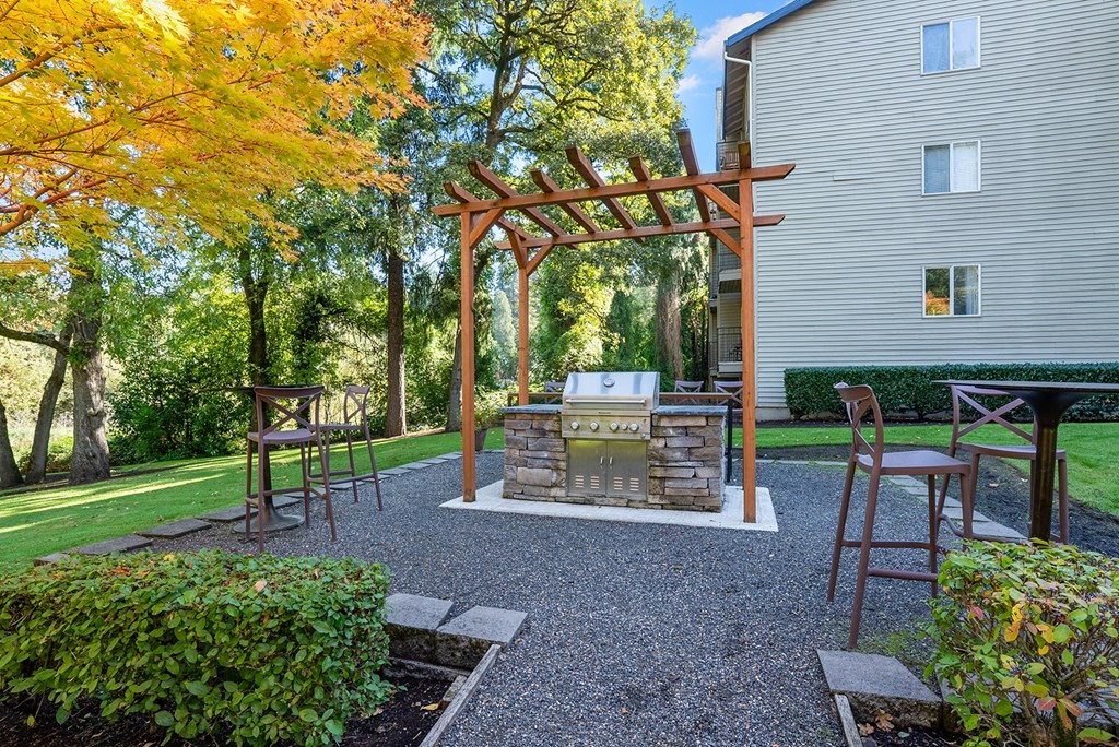 BBQ area with greenery and an apartment building in the background