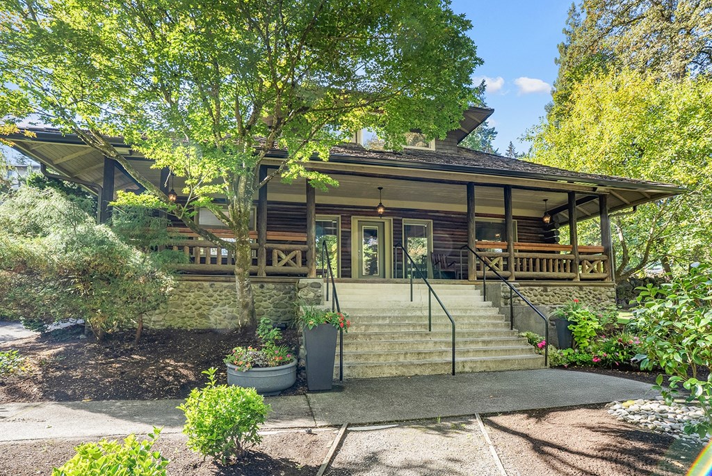 Building with a front porch and a tree in front.