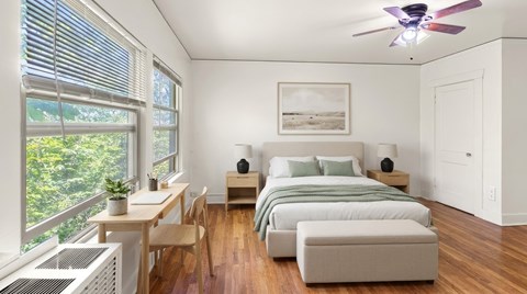 A bedroom with a bed, a table, and a ceiling fan.
