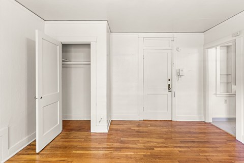 A room with white walls and wood floors with a door open to a hallway.