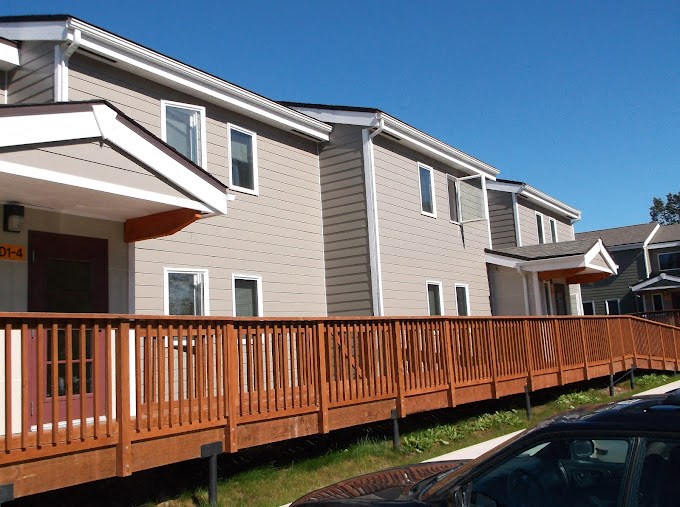 an apartment home with a wooden fence in front of it at Conifer Woods Apartments, Alaska