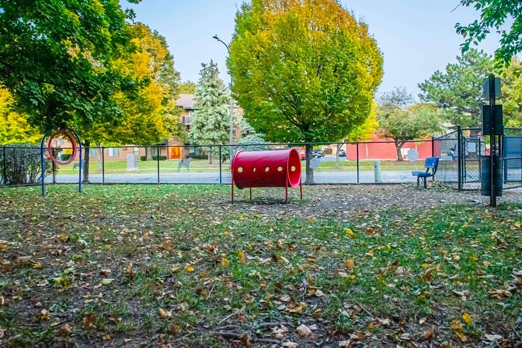 a playground with a red bench and trees in the background at Fifteen 98 Naperville, Naperville, IL