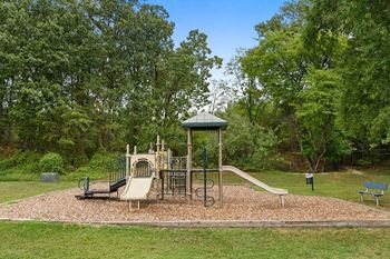a playground with a swing set and slides in a park