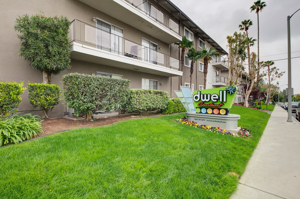 a lawn with a sign in front of an apartment building at Dwell Apartment Homes, Riverside, CA, 92507
