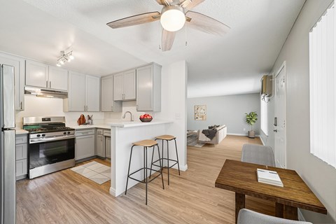 A kitchen with a refrigerator, stove, and bar stools.