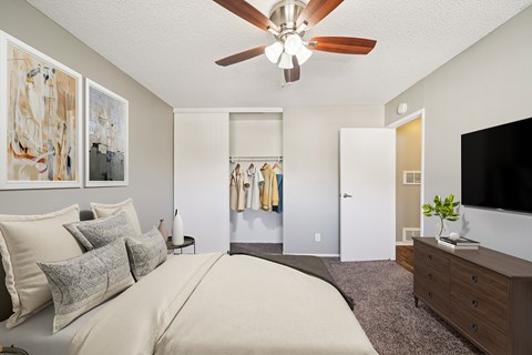 A bedroom with a large bed, a ceiling fan, and a television.