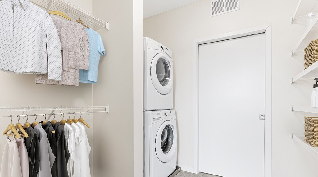 A laundry room with clothes hanging up and a washing machine.
