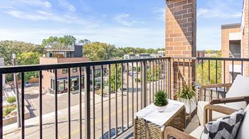 A balcony with a table and chairs overlooking a street.