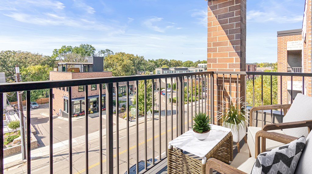 A balcony with a table and chairs overlooking a street.