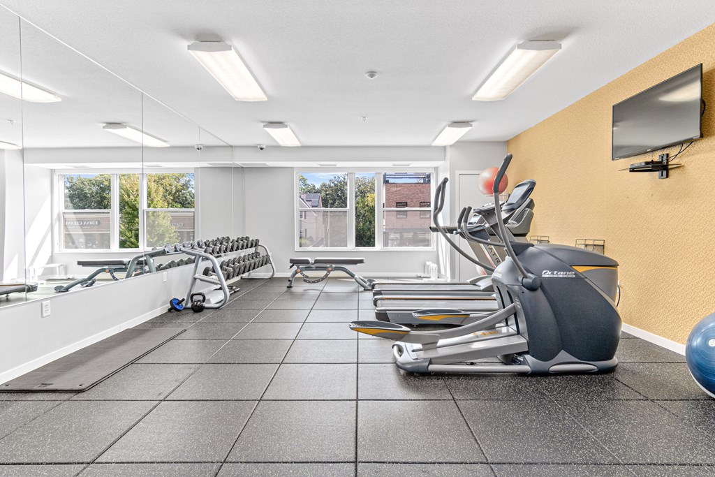 A gym with treadmills, exercise bikes, and a television.