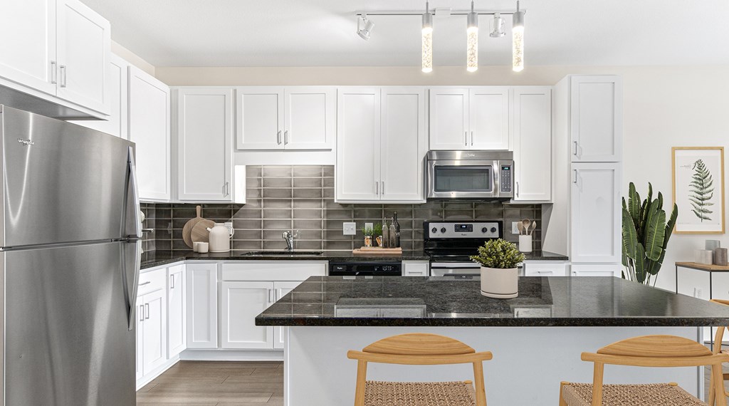 A modern kitchen with a black countertop and white cabinets.
