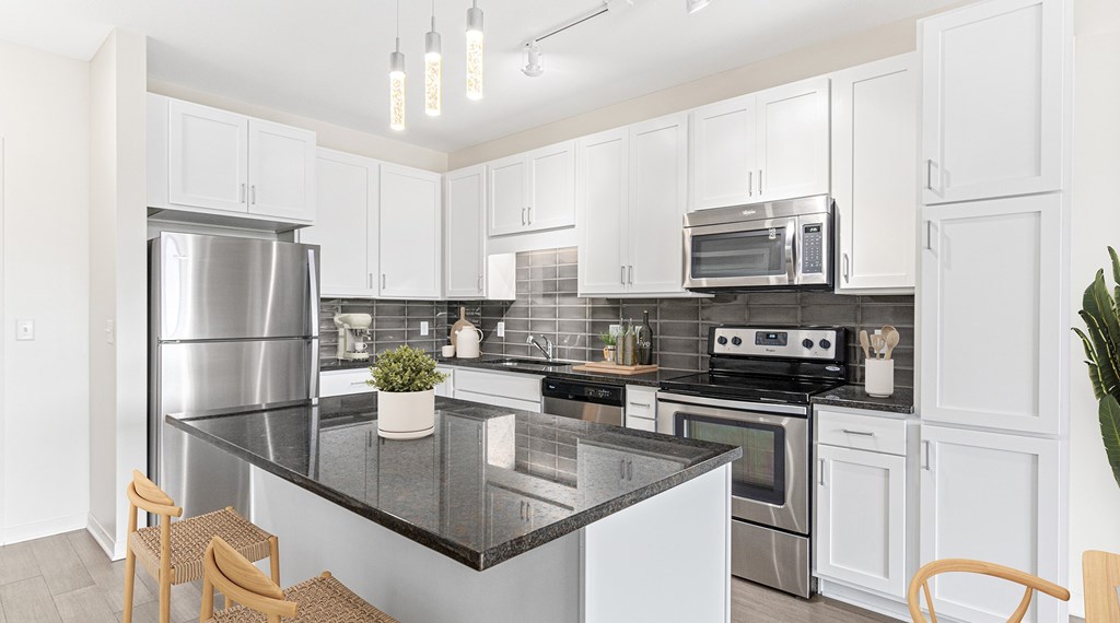 A modern kitchen with a black countertop and stainless steel appliances.