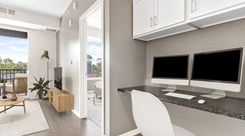 A modern home office with a desk, chair, and computer monitors.