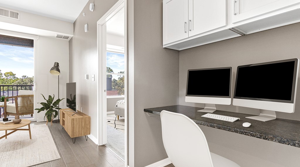 A modern home office with a desk, chair, and computer monitors.