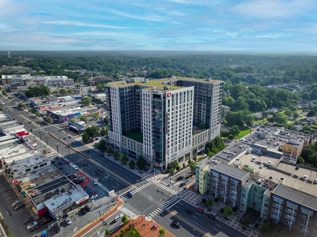 A large building with a red logo on the side is surrounded by other buildings and roads.