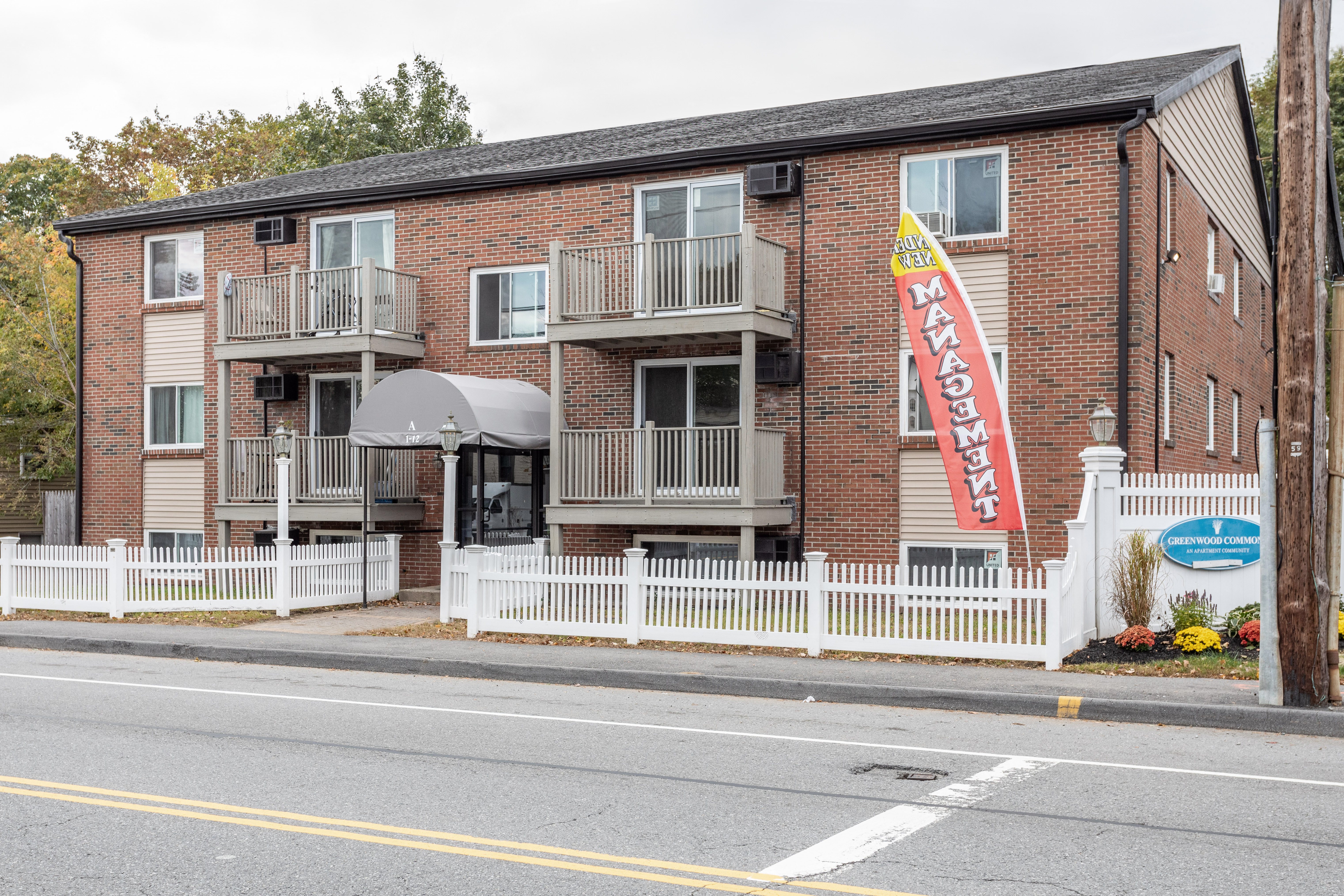 an apartment building with a red brick facade and a sign in front at Flats at Merrill Pond, Worcester