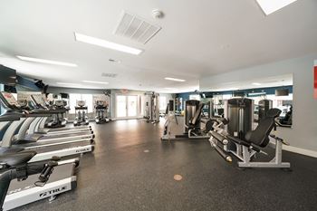 a gym with cardio equipment and weights on the floor