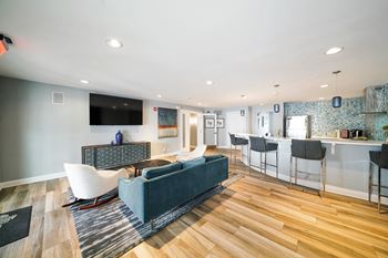A living room with a blue couch and a television on the wall.