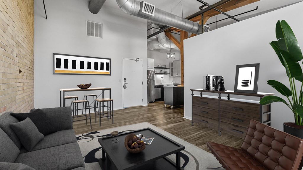A modern living room with a grey couch, a black coffee table, and a brown leather chair.