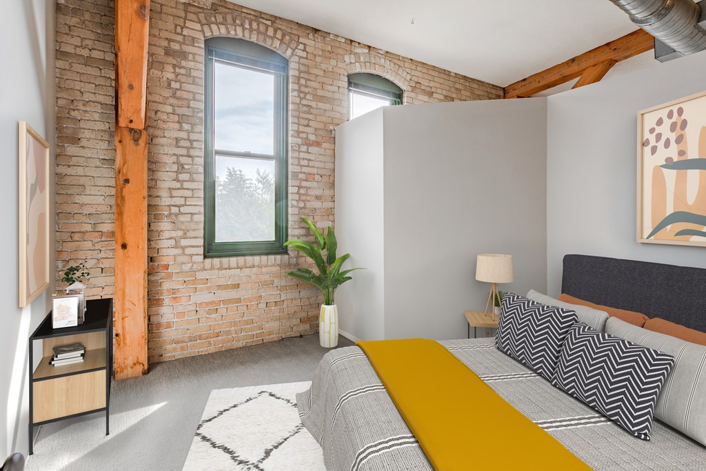 A bedroom with a bed, nightstand, and a window.