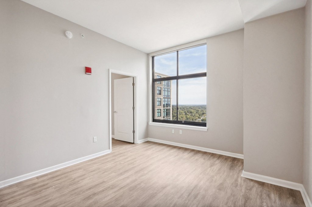 an empty living room with a large window and wood flooring