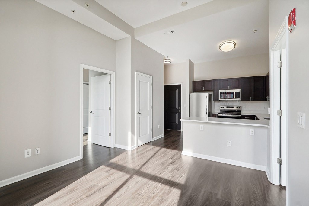living room and kitchen of a apartment with white walls and wood floors