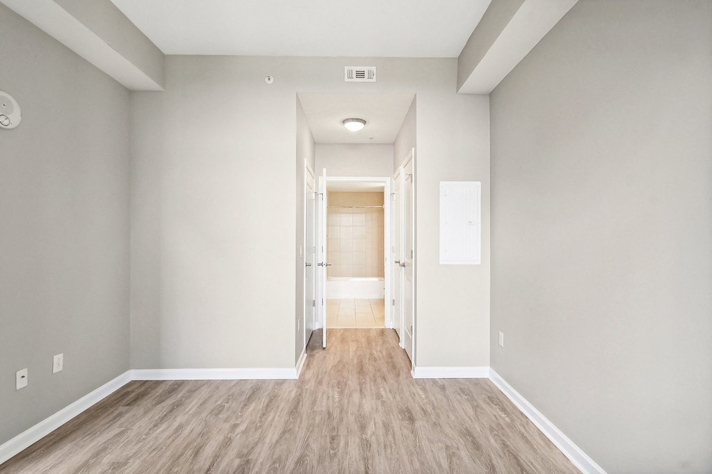 an empty bedroom with white walls and wood flooring