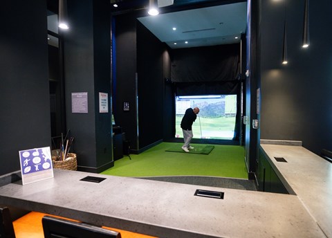 Man playing on a golf simulator at Arrive Federal Hill