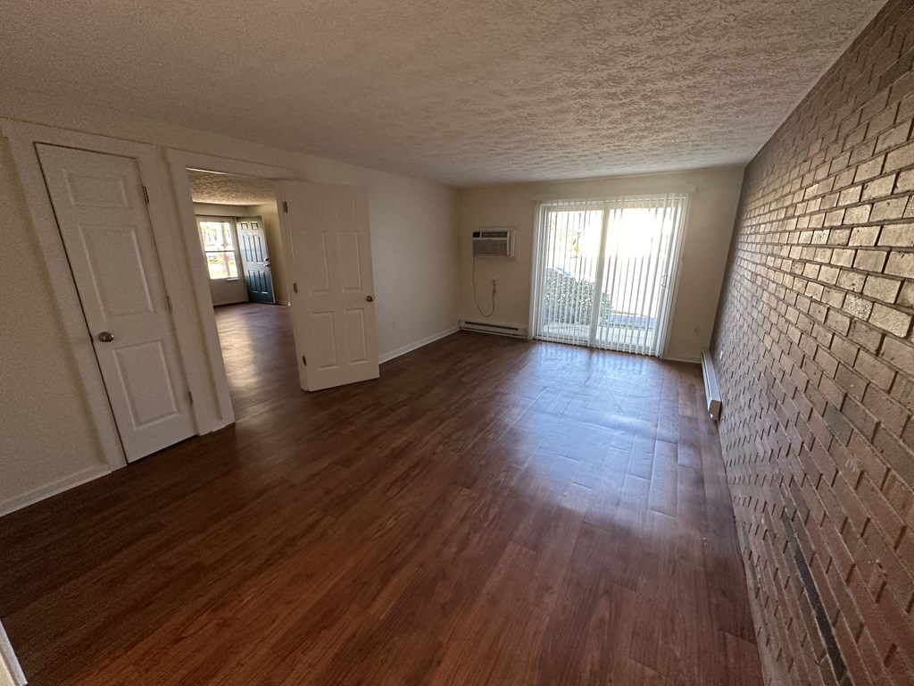 an empty living room with a brick wall and wooden floors
