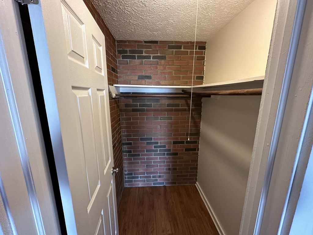 a small hallway with a brick wall and wooden floors