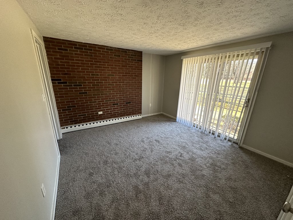 an empty living room with a brick wall and a window