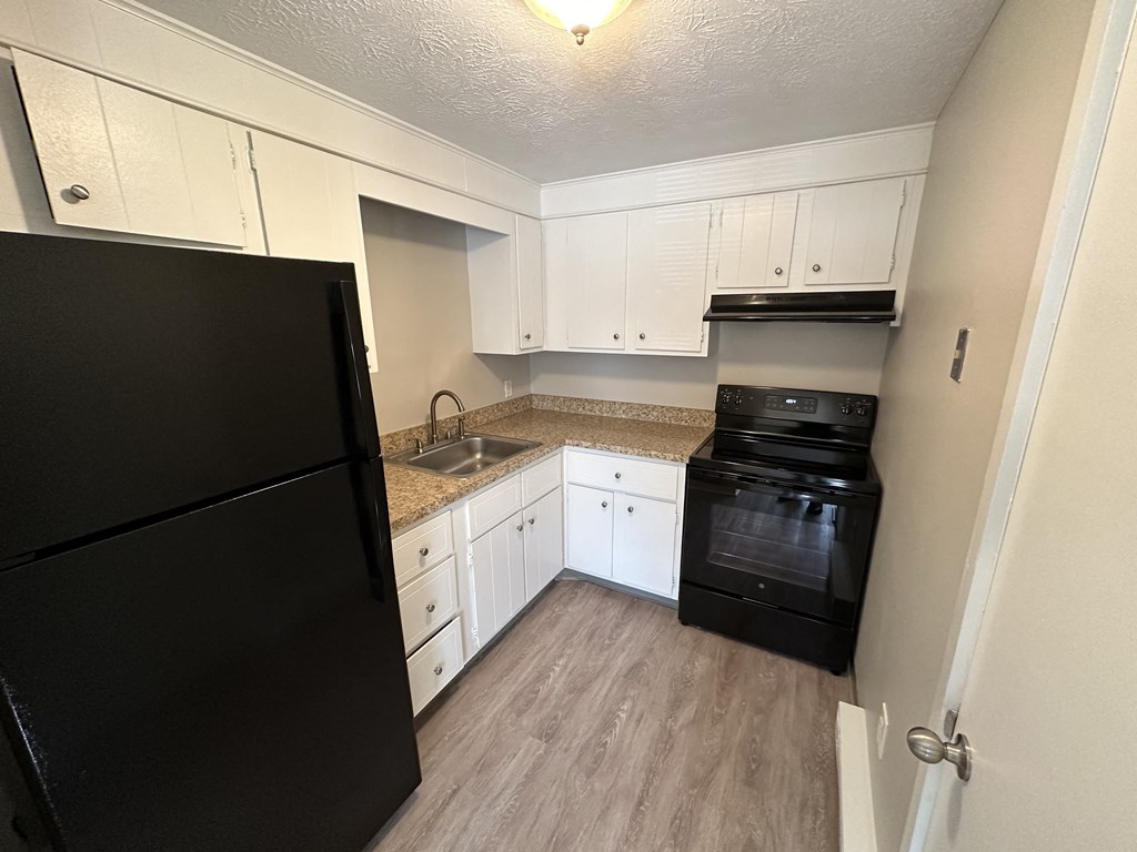 a kitchen with white cabinets and black appliances