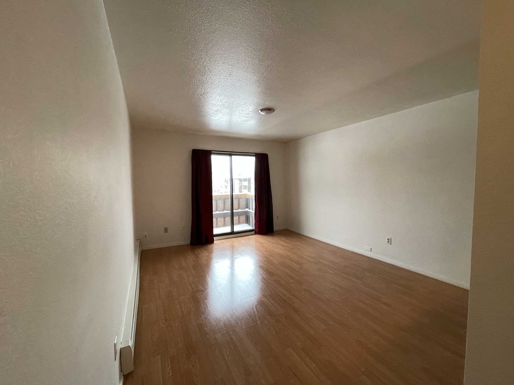 an empty living room with wood floors and a window