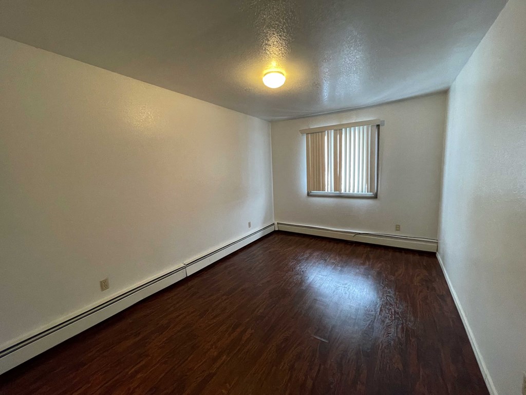 a empty living room with wood flooring and a window