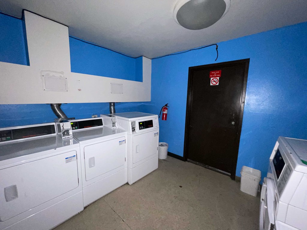 a laundry room with four washes and a black door